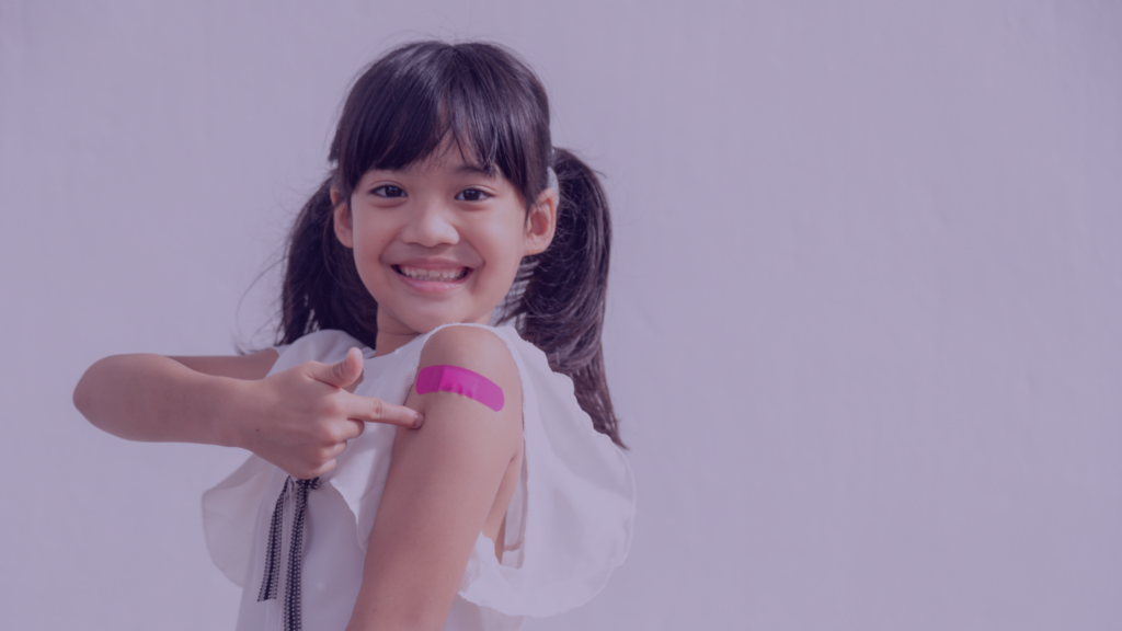 little girl pointing to her band aid after getting a shot